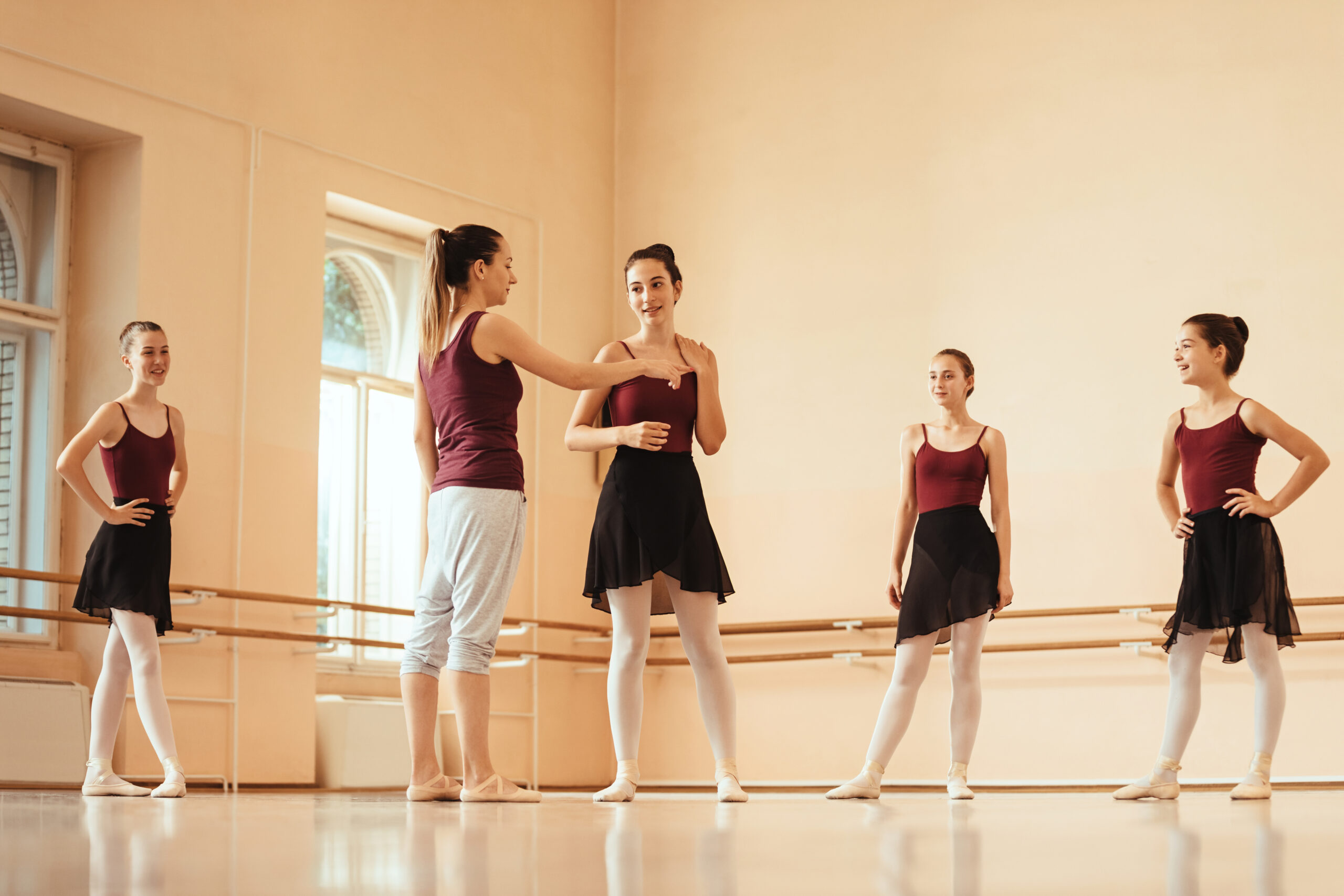 ballet instructor holding a class to group of ballerinas and communicating with them at dance studio.